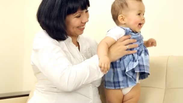 Bebê sorridente com a mãe sentada no sofá — Vídeo de Stock