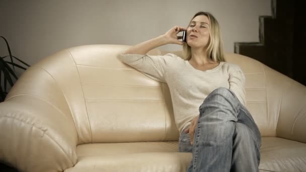 Beautiful girl on sofa speaking by phone — Stock Video