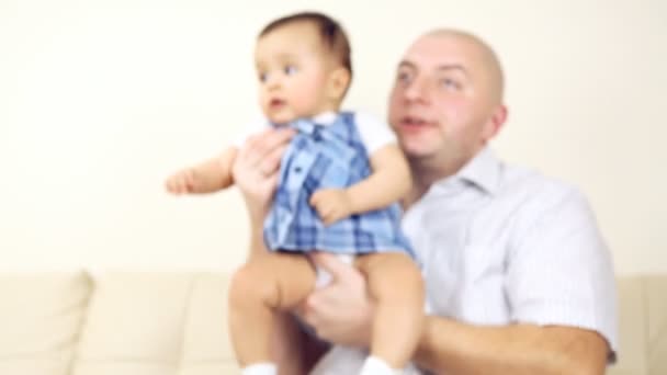 Usmívající se dítě s otcem sedí na pohovce — Stock video