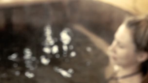 Femme assise dans l'eau chaude en plein air en hiver 