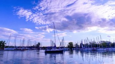 BADACSONY, HUNGARY - 18 Eylül 2021: Balaton Gölü 'nün ve Macaristan' ın Badacsony kentinde gün batımında rıhtımdaki gemilerin hızlandırılmış görüntüsü.