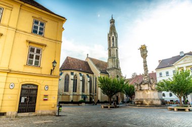 SOPRON, HUNGARY - 13 Ağustos 2021: Güneşli bir günde Macaristan 'ın Sopron kentinde Kutsanmış Mary Benedictine Kilisesi veya Soproni Nagyboldogasszony fırtına ve sokakları.