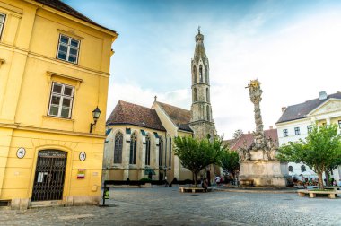 SOPRON, HUNGARY - 13 Ağustos 2021: Güneşli bir günde Macaristan 'ın Sopron kentinde Kutsanmış Mary Benedictine Kilisesi veya Soproni Nagyboldogasszony fırtına ve sokakları.