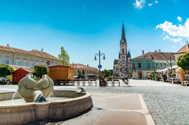 KOSZEG, HUNGARY - 14 Ağustos 2021: Güneşli, bulutlu bir yaz gününde Kutsal Kalp Kilisesi veya Koszegi Jezus szive plebaniatwork ve Main Squre veya Fo ter 'deki insanlar.