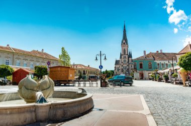 KOSZEG, HUNGARY - 14 Ağustos 2021: Güneşli, bulutlu bir yaz gününde Kutsal Kalp Kilisesi veya Koszegi Jezus szive plebaniatwork ve Main Squre veya Fo ter 'deki insanlar.