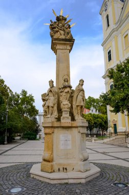 Güneşli bir günde Zalaegerszeg 'deki Mary Magdalene Kilisesi' nin önündeki Kutsal Üçlü Heykel..