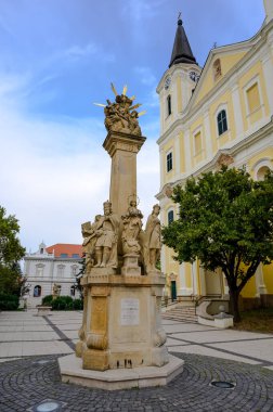 Güneşli bir günde Zalaegerszeg 'deki Mary Magdalene Kilisesi' nin önündeki Kutsal Üçlü Heykel..
