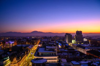Gün batımında gökdelenden Ljubljana şehrine bakın. Arka planda dağlar var..