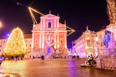 LJUBLJANA, SLOVENIA - 15 HAZİRAN 2022: Preseren Anıtı ve Fransisken Kilisesi 'ne gece vakti insanlar Preseren Meydanı' nda yürürken bakın