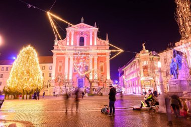 LJUBLJANA, SLOVENIA - 15 HAZİRAN 2022: Preseren Anıtı ve Fransisken Kilisesi 'ne gece vakti insanlar Preseren Meydanı' nda yürürken bakın