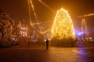 LJUBLJANA, SLOVENIA - 15 HAZİRAN 2022: Sisli bir Noel akşamı Preseren Meydanı 'nda yürüyen insanları görmek