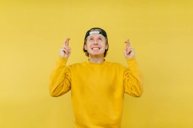 Parlak kazaklı genç adam sarı bir arka planda elinde bir banka kartıyla duruyor, kameraya bakıyor yüzünde bir gülümsemeyle ve şöyle bir jest yapıyor:.