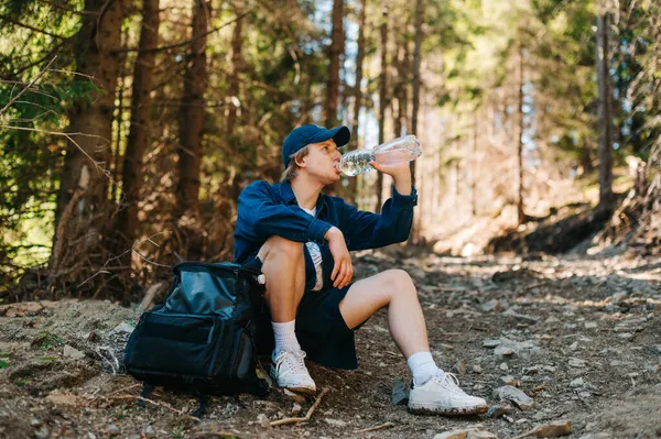 Yakışıklı Genç Turist Dağlarda Bir Patikada Sırt Çantasıyla Oturur Bir — Stok fotoğraf