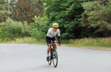 Fotoğraf, asfalt yolda bisiklet süren bir bisikletçinin hızında çekilmiş. Hareket halindeki bir bisikletçinin fotoğrafı