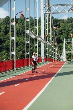 Güneşli bir yaz gününde, köprüdeki bisiklet yolunda profesyonel bisikletçiler. Dikey. Bisiklet bir hobidir.