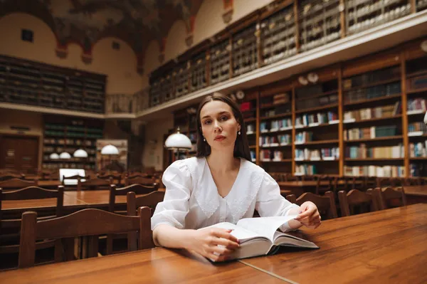 Приваблива Жінка Сидить Публічній Бібліотеці Книгою Руках Позує Камеру Серйозним — стокове фото