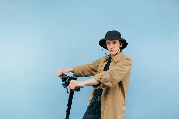 Zabawny Młody Człowiek Koszuli Elektronicznym Skuterze Jeździ Niebieskim Tle Patrzy — Zdjęcie stockowe
