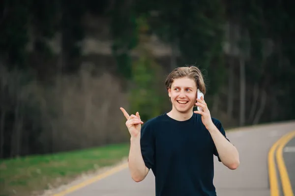 Позитивний Молодий Чоловік Чорній Футболці Прогулянці Горах Розмовляє Телефону Посмішкою — стокове фото