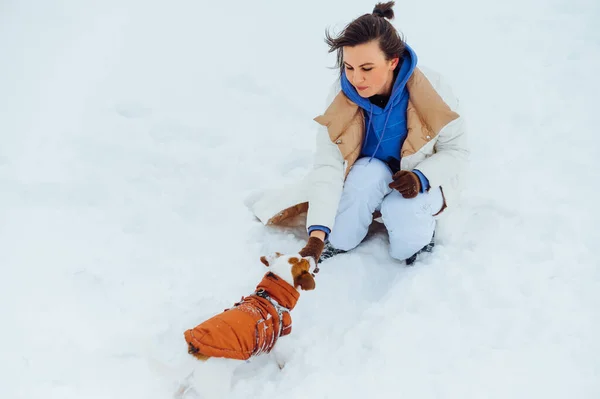 Όμορφη Γυναίκα Παίζει Ένα Σκύλο Τζακ Ράσελ Στο Χιόνι Ενώ — Φωτογραφία Αρχείου