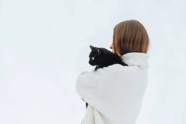 Egy Pulóveres Hölgy Hátterében Pózol Egy Fekete Macskával Utcán Félrenéz — Stock Fotó