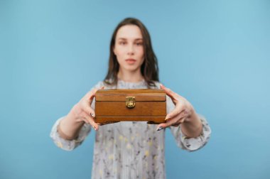 Güzel esmer kadın kameraya güzel ahşap bir kutu gösterir. Ellerindeki konuya odaklanır..