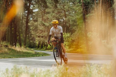 Aktif genç adam bisikletle ormanda bir dağ yolunda bisiklet sürüyor..