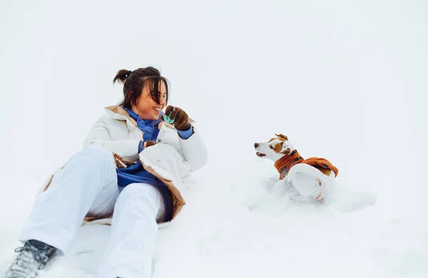 Mulher Alegre Divertindo Com Pequeno Cão Jack Russel Deitado Neve — Fotografia de Stock