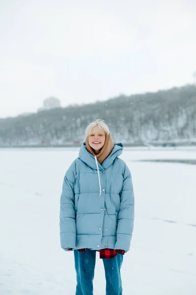 Pozitivní Dívka Teplém Oblečení Stojí Sněhu Sněhu Pozadí Zamrzlé Řeky — Stock fotografie