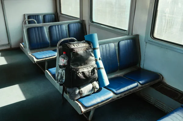 Tourist backpack with yoga mat and sleeping bag in an empty old train. Vertical