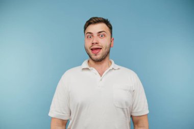 Mavi arka planda tüyleri olan komik aptal adam kameraya bakıyor ve gülüyor..