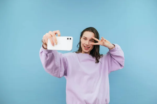 Menina Atraente Uma Camisola Roxa Leva Uma Selfie Fundo Azul — Fotografia de Stock