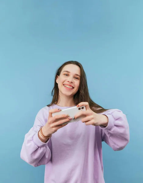 Jogador Menina Feliz Com Smartphone Mãos Isoladas Fundo Azul Olha — Fotografia de Stock