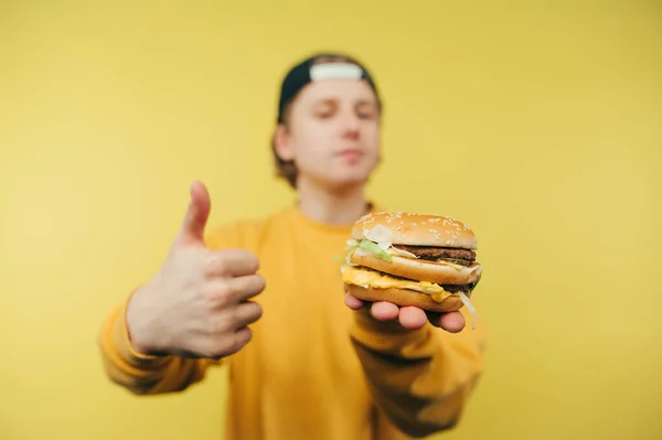 배경의 남자는 식욕을 돋우는 버거를 동작을 줍니다 남자가 패스트푸드 점에서 — 스톡 사진