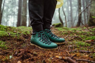 Botlu turist, ormanın ıslak zemininde, yosunların arka planında, yakın plan fotoğrafında duruyor..