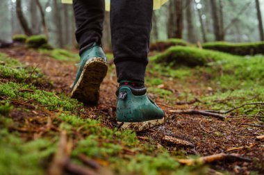 Ormanda yürüyüş yaparken ıslak zeminde yosun tutarak yürüyen bir turistin ayaklarının yakın fotoğrafını çek.