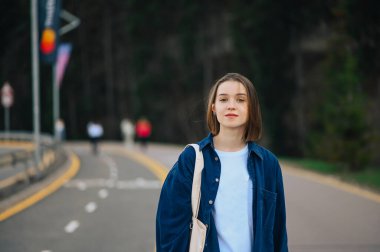 Çekici bayan tatilde dağlarda yürüyor ormanın arka planına karşı yolda, kameraya bakıyor..