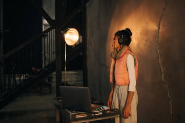 Kulaklıklı bir kadın DJ bir partide kumandada müzik çalar, müzik yapar..