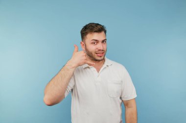 Tüylü olumlu bir adam mavi arka planda gülümseyen, izole bir telefon konuşması yapıyor.