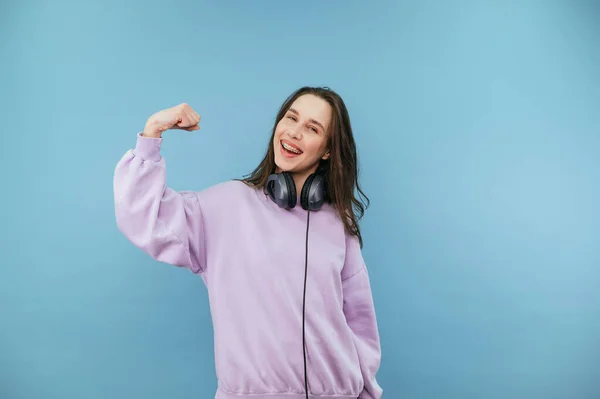 Aantrekkelijk Brunette Meisje Paarse Trui Hoofdtelefoon Toont Biceps Naar Camera — Stockfoto