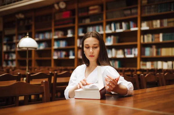 Приваблива Студентка Читає Книгу Сидячи Столом Серйозним Обличчям Бібліотеці Університетського — стокове фото