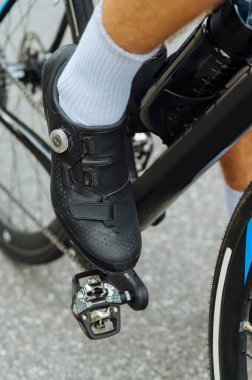 Pedaldaki profesyonel bir bisikletçinin kontak bisiklet ayakkabılarının yakın fotoğrafı. Dikey