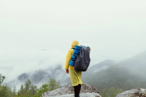 Tourist Guy Yellow Raincoat Backpack Stands Rock Backdrop Mountain Cloud — Stock Photo, Image