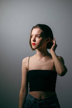 Geceleyin bir partide makyajlı çekici bir kadının dikey portresi gri bir duvara yaslanmış ve başka tarafa bakıyor.