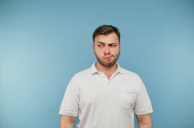 Sırıtan kıllı komik yetişkin bir adam mavi arka planda izole bir şekilde fotokopi alanına bakıyor.