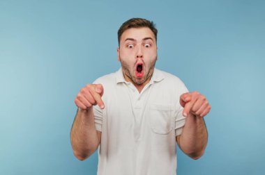 Mavi arka planda beyaz tişörtlü, duygusal deli bir adamın portresi. Şok olmuş yüz ve başparmaklar aşağı bakıyor.