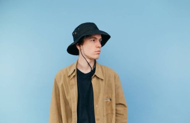 Panamalı yakışıklı genç adam mavi arka planda izole, ciddi bir yüz ile yana bakıyor