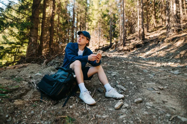 Mladý Muž Košili Sedí Lese Stezce Zatímco Leze Horu Batohem — Stock fotografie
