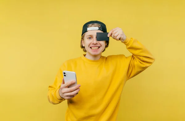 Junger Mann Gelbem Sweatshirt Mit Smartphone Und Kreditkarte Der Hand — Stockfoto