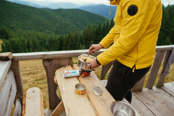 Erkek turist, güzel manzaralı bir tencerede ocağın üstünde, dağlarda makarna hazırlıyor..