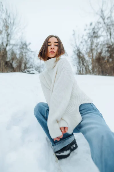 Жіноча Модель Джинсах Язаний Светр Позує Сидячи Снігу Відкритому Повітрі — стокове фото